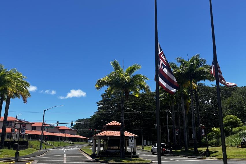 晴れ渡る青空とアスファルトの道路。右側にはハワイ州旗とアメリカ国旗がポールの中ほどに掲げられている。
