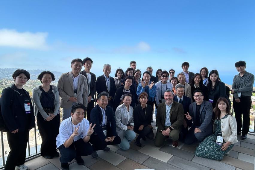 A group of SAF and Asian university reps pose on a balcony overlooking UC San Diego campus.