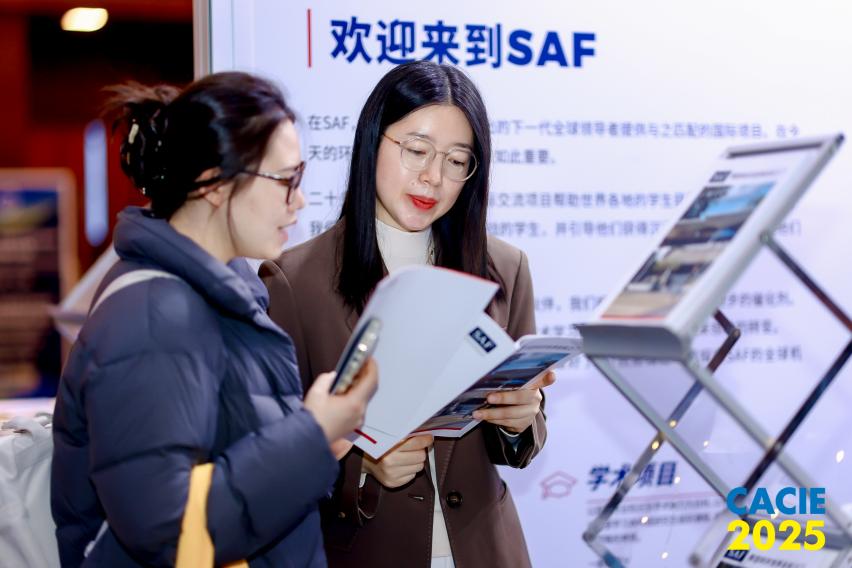 An SAF China staff member shows someone informational materials at CACIE 2025 in Beijing.