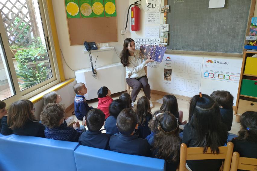A student in her teaching internship reads a picture book to a group of school children.