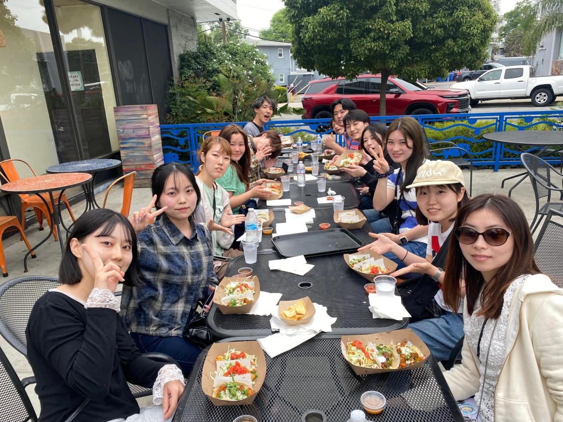 A group of students at a long table, eating tacos.