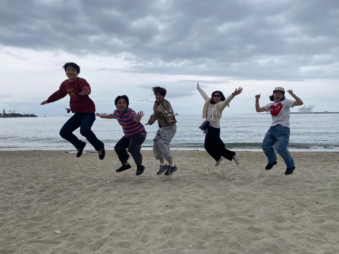 Five students jumping on a California beach.