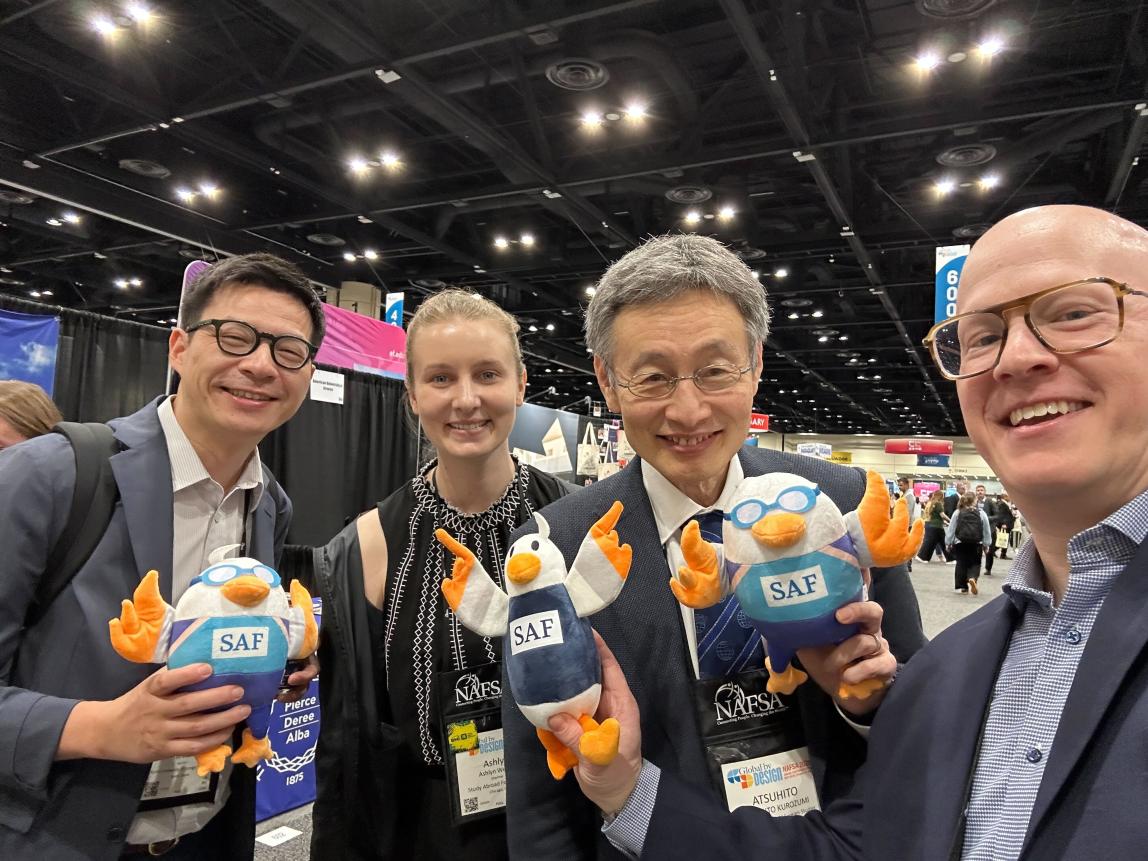 SAF staff with university partners at NAFSA 2026, holding up SAFFY dolls.