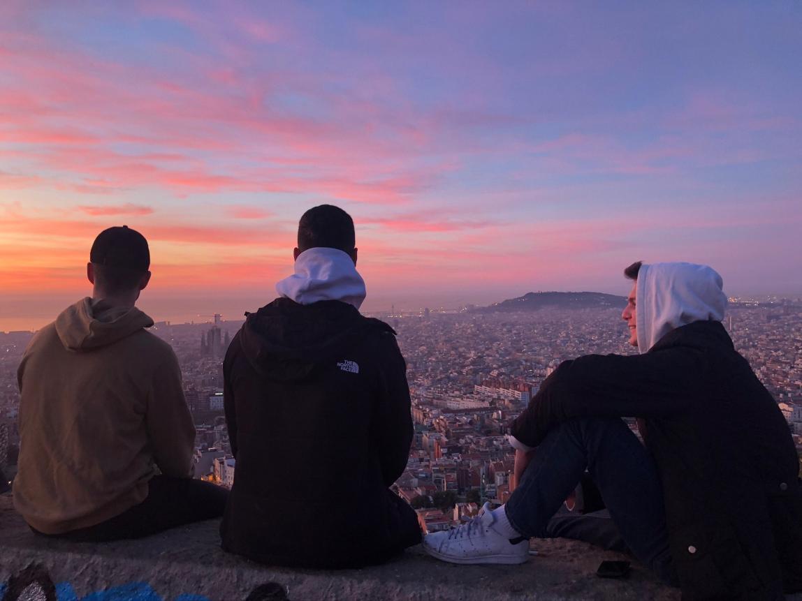 three male students look out over Barcelona from the Bunkers