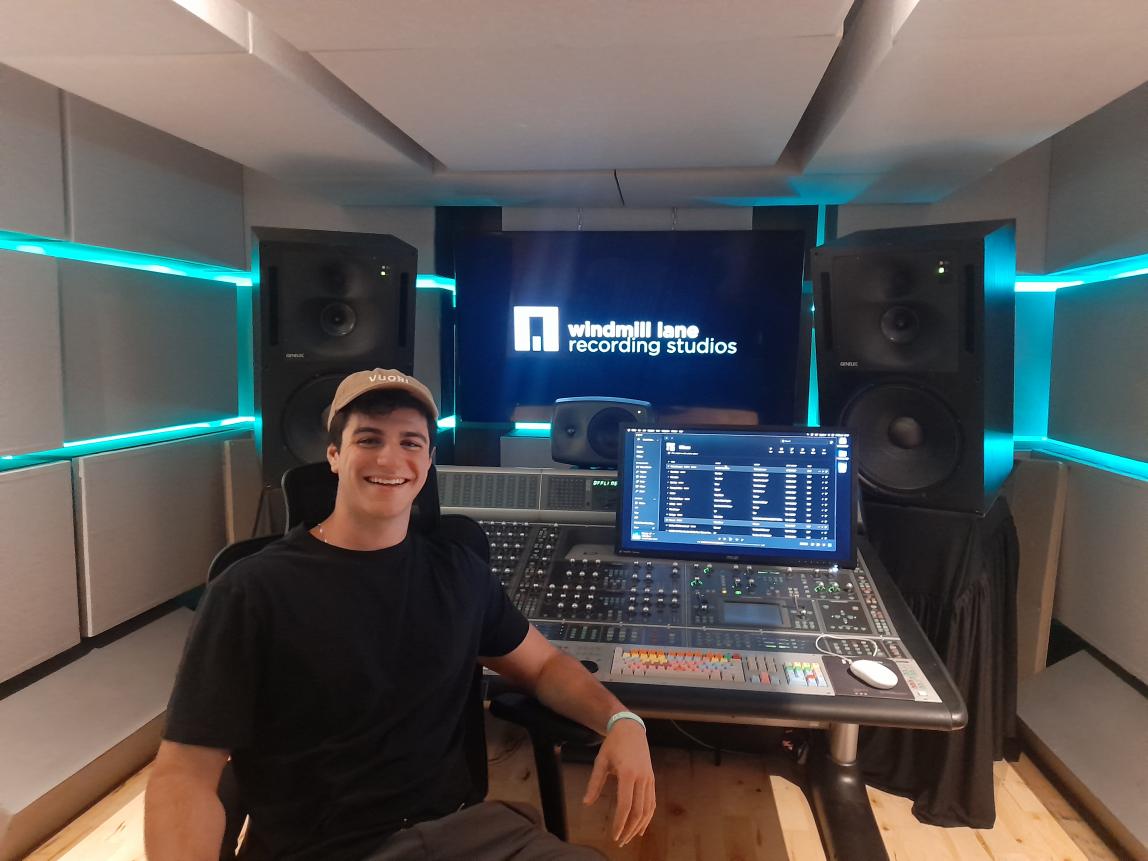 student smiling with hat on in front of audio visual equipment