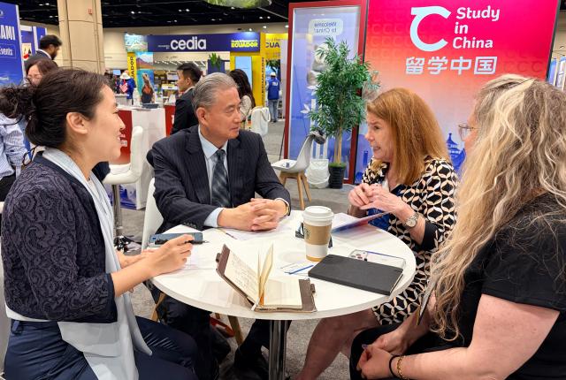 SAF leadership chatting with university partners around a table inside convention.