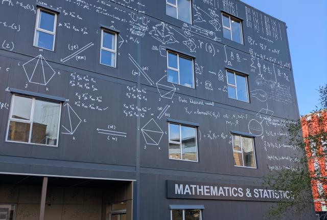 数式や記号が壁面全体に刻まれたグレーの「数学・統計学科」の建物