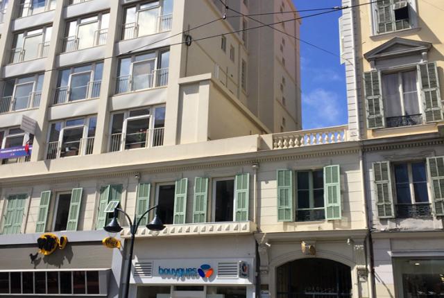 The exterior of a white windowed six story building adjoined to a four story yellow building.