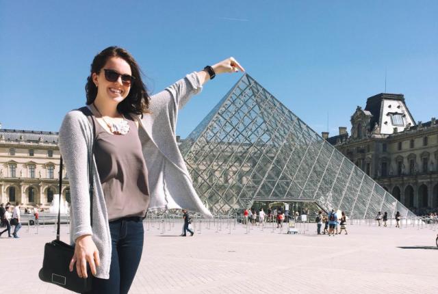 Student at an angle that looks like she is touching the top of the Louvre 