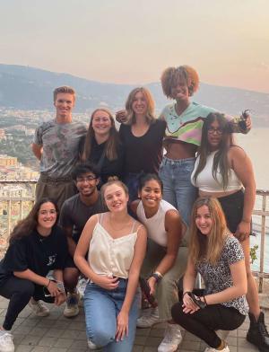 A group of diverse students smiling at the camera atop a balcony in Verona.