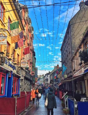 irish side streed at sunset lined with pubs, brick buildings, and a blue sky