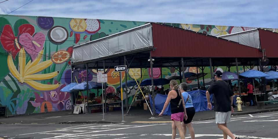 アメリカ、ハワイのマーケットの様子。カラフルにペイントされた壁の前に並ぶ色とりどりのパラソルやテント。